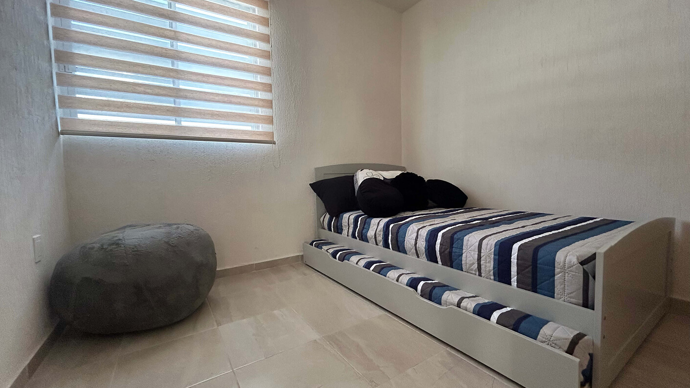 recamara con un sillon y una cama individual de casa modelo napa en desarrollo residencial paseos de los viñedos en el estado de Aguascalientes Mexico