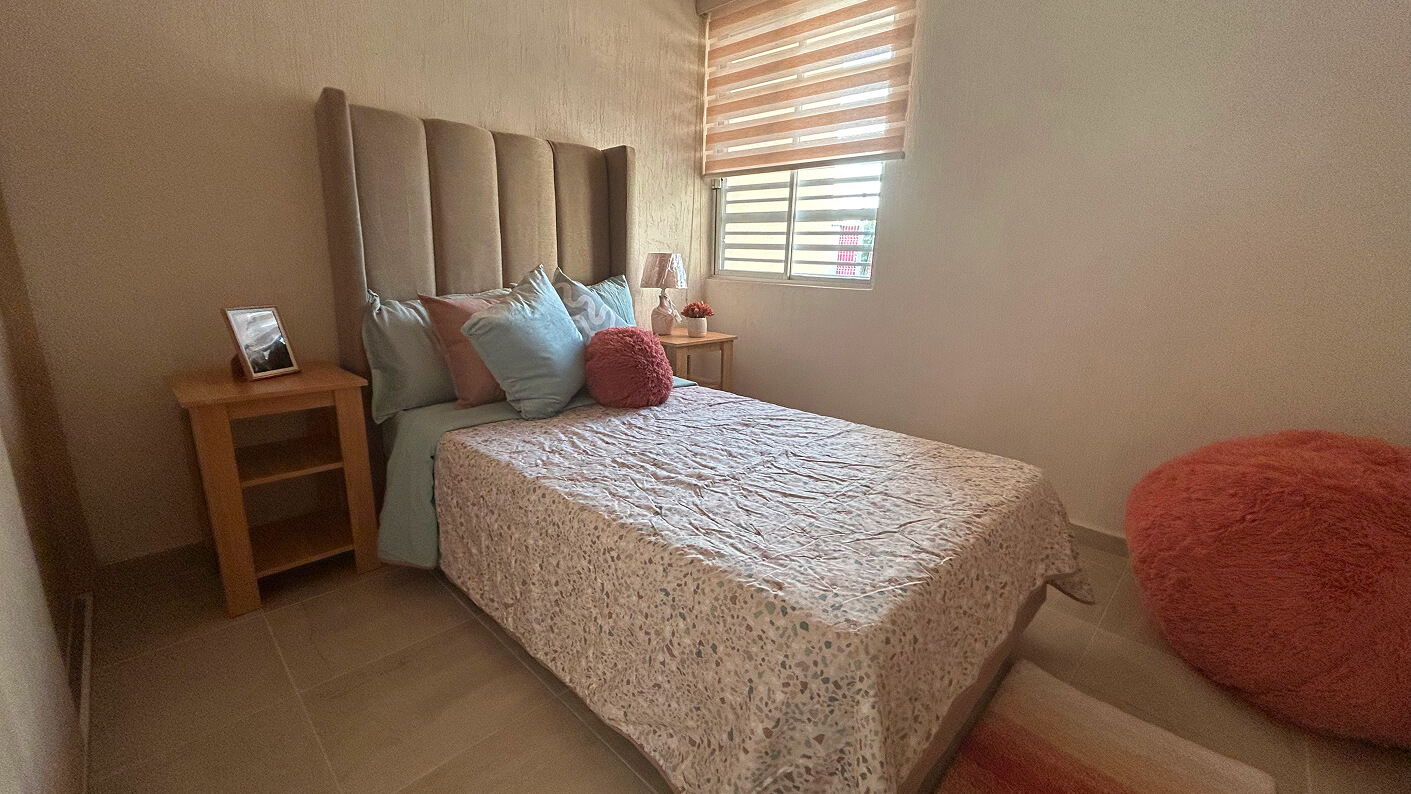 recamara con cama matrimonial dos buros un cojin sillon y una ventana de casa modelo bonart en desarrollo residencial paseos de los viñedos en el estado de Aguascalientes Mexico del desarrollo inmobiliario frindsa